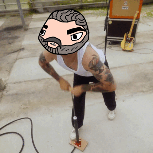 A Man With A Cartoon Face On His Head Is Standing In Front Of An Orange Amplifier GIF