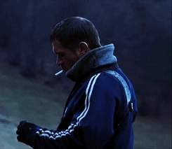 a man with a cigarette in his mouth wearing a blue adidas jacket
