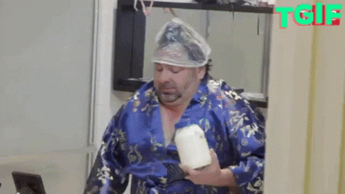 A Man With A Condom On His Head Is Holding A Candle . GIF
