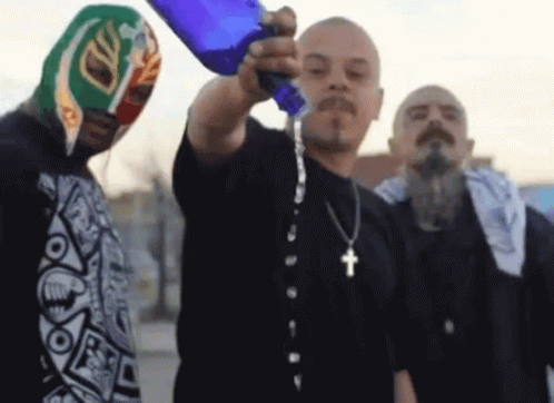 A Man With A Cross Necklace Pours Water Into Another Man 'S Face GIF