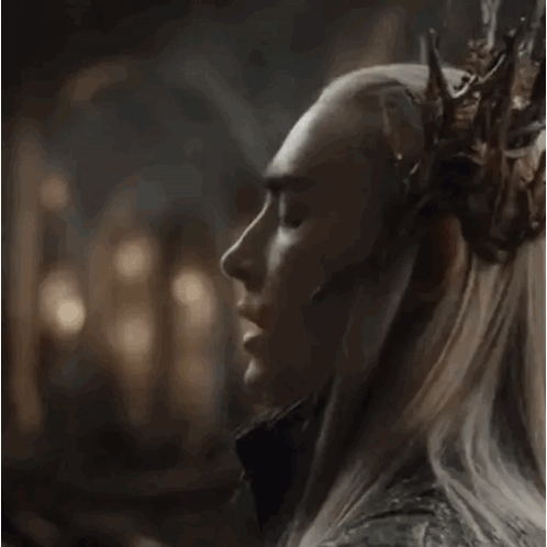 a man with a crown on his head is looking at the camera and says what do you think .