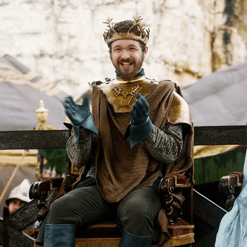 A Man With A Crown On His Head Is Sitting On A Chair GIF