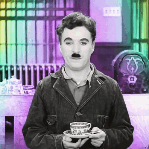 A Man With A Fake Mustache Is Holding A Cup And Saucer GIF