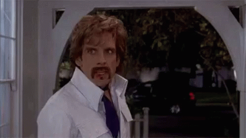 A Man With A Fake Mustache Is Standing In Front Of A Doorway . GIF