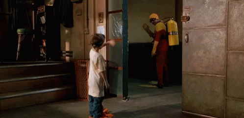 A Man With A Fire Extinguisher On His Back Is Standing Next To A Boy In A Room GIF