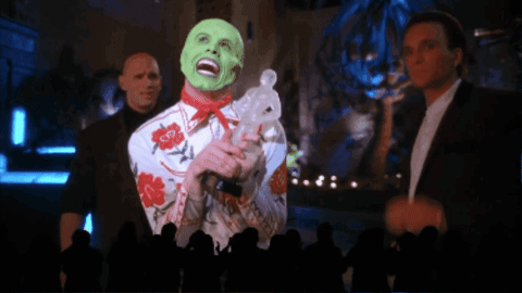 A Man With A Green Mask Is Holding A Rabbit In Front Of A Crowd GIF
