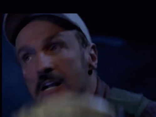 a man with a hat on is eating popcorn in a dark room .
