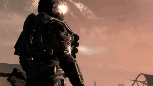 A Man With A Helmet On Stands In Front Of Mountains GIF