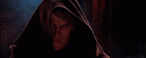 A Man With A Hood On His Head Is Looking At The Camera With A Serious Look On His Face . GIF