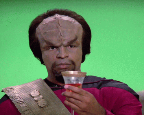 A Man With A Huge Head Is Holding A Glass Of Wine GIF