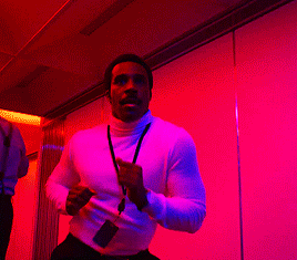 a man with a lanyard around his neck is running in a room with purple lights