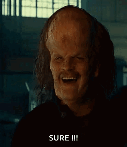 A Man With A Large Bald Head Is Pointing At The Camera And Says Sure GIF