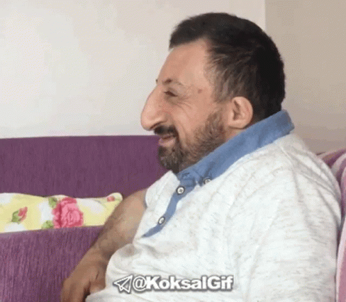 A Man With A Large Nose Is Sitting On A Purple Couch With The Hashtag @Koksalgif GIF