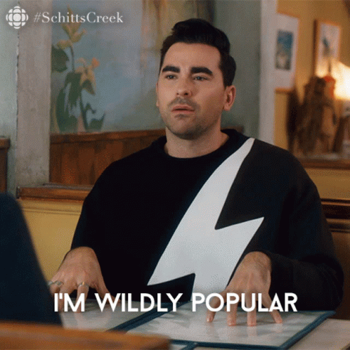 A Man With A Lightning Bolt On His Shirt Is Sitting At A Table And Says " I 'M Wildly Popular " GIF