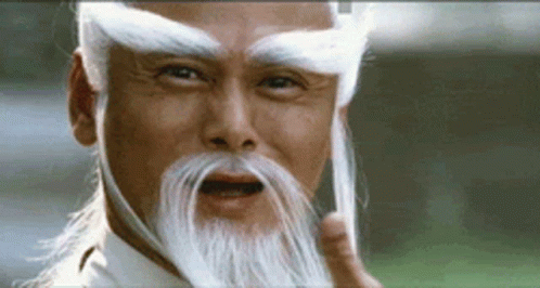 A Man With A Long White Beard And Eyebrows Is Making A Funny Face . GIF