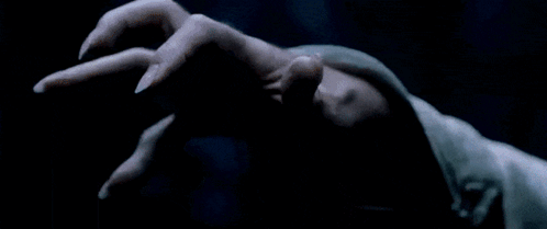 A Man With A Long White Beard Is Holding Something In His Hand In A Dark Room GIF