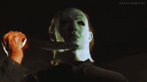 a man with a mask holds a knife to his neck and the words angelicamyers are above him