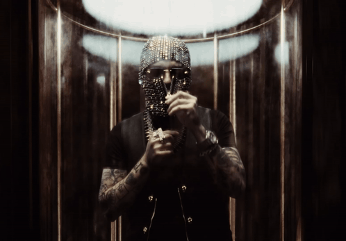 A Man With A Mask On His Face Is Standing In A Dark Room GIF
