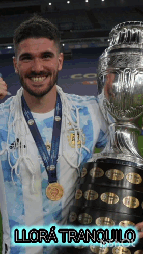 A Man With A Medal Around His Neck Is Holding A Trophy And Says Llora Tranquilo GIF