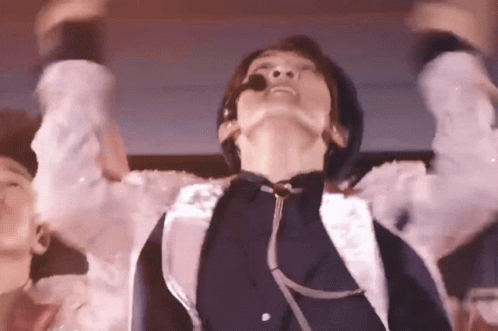 A Man With A Microphone In His Mouth Is Dancing On A Stage . GIF
