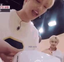 A Man With A Microphone On His Ear Is Holding A White Object In His Hands . GIF
