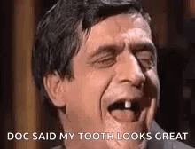 A Man With A Missing Tooth Is Laughing With His Mouth Open And His Tongue Out . GIF