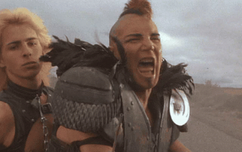 A Man With A Mohawk And Feathers On His Shoulder Screams GIF