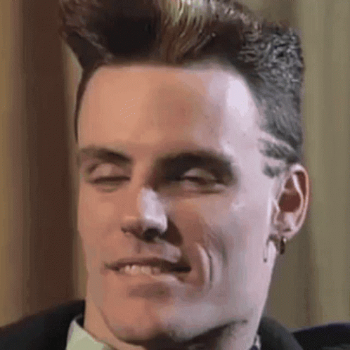 A Man With A Mohawk Is Smiling With His Eyes Closed . GIF