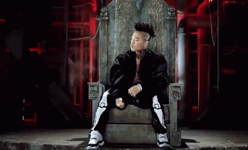 a man with a mohawk sits on a throne