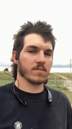 A Man With A Mullet And A Beard Is Wearing A Black Shirt GIF
