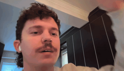 A Man With A Mullet And A Mustache Is Wearing Ear Buds GIF