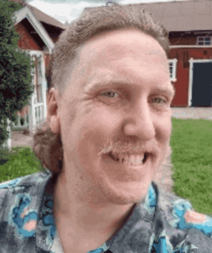 A Man With A Mullet And A Mustache Smiles In Front Of A Red Barn GIF