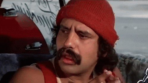 A Man With A Mustache And A Red Beanie Is Sitting In The Back Seat Of A Car . GIF