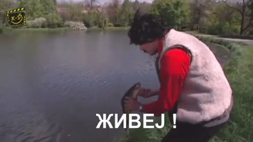 A Man With A Mustache And A Red Jacket Is Standing In Front Of A Tree And Says Живоj ! GIF