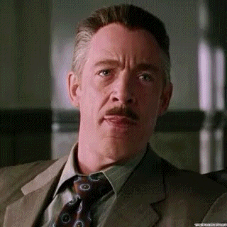 A Man With A Mustache And A Suit And Tie Is Making A Funny Face . GIF