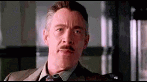 A Man With A Mustache And A Suit And Tie Is Making A Funny Face . GIF