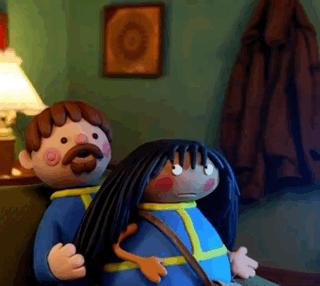 A Man With A Mustache And A Woman With Long Black Hair Are Sitting On A Couch GIF