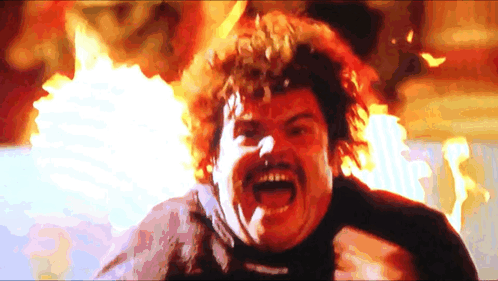 A Man With A Mustache And Curly Hair Is Screaming In Front Of A Fire GIF