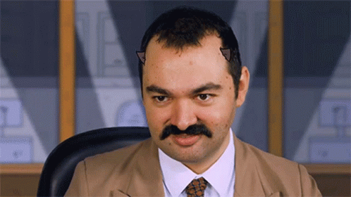 A Man With A Mustache And Horns On His Head Looks At The Camera GIF