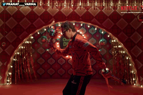 A Man With A Mustache And Sunglasses Is Dancing In Front Of A Red Wall With Netflix Written On It GIF