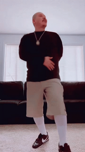 A Man With A Mustache Is Dancing In A Living Room GIF