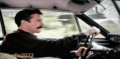 A Man With A Mustache Is Driving A Car In A Photo Taken By Cravello20203 GIF