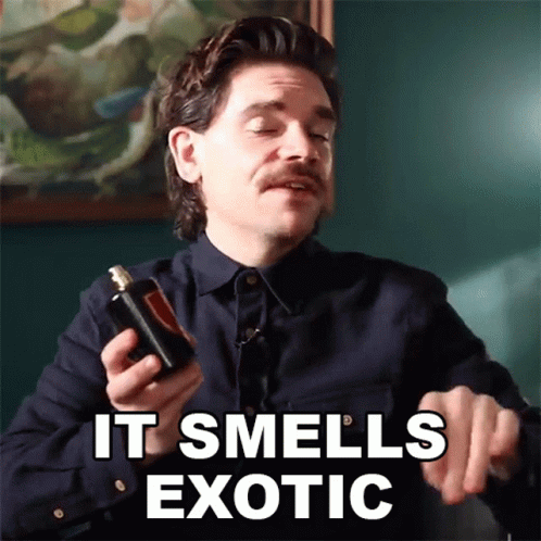 A Man With A Mustache Is Holding A Bottle Of Perfume And Says It Smells Exotic GIF