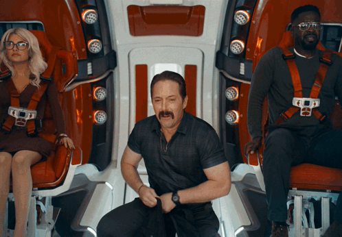 A Man With A Mustache Is Kneeling Down In Front Of A Woman Sitting In A Chair GIF