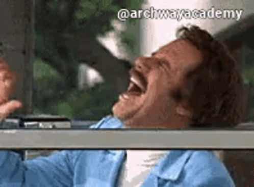a man with a mustache is laughing with his mouth open while sitting in a car .