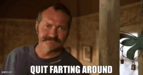 A Man With A Mustache Is Looking At The Camera With The Words Quit Farting Around Below Him GIF