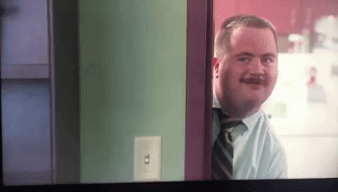 A Man With A Mustache Is Looking Through A Doorway GIF