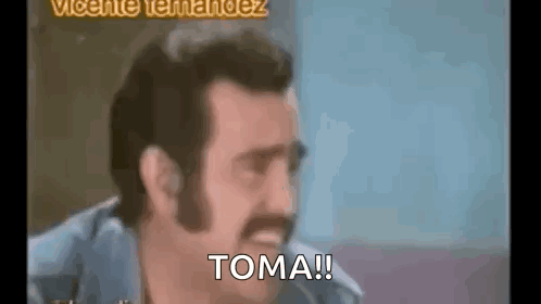 a man with a mustache is making a funny face and says `` toma '' .