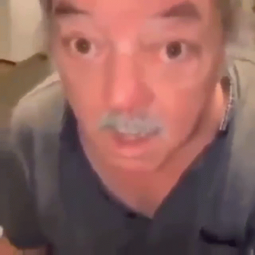 A Man With A Mustache Is Making A Funny Face While Looking At The Camera . GIF