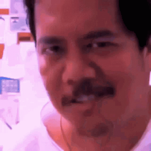 A Man With A Mustache Is Making A Funny Face While Looking At The Camera . GIF
